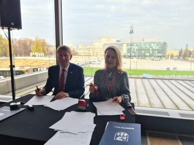 Podpisanie umowy. W tle Plac Marszałka Józefa Piłsudskiego, Grób Nieznanego Żołnierza i rozpoczęta budowa Pałacu Saskiego w Warszawie. 